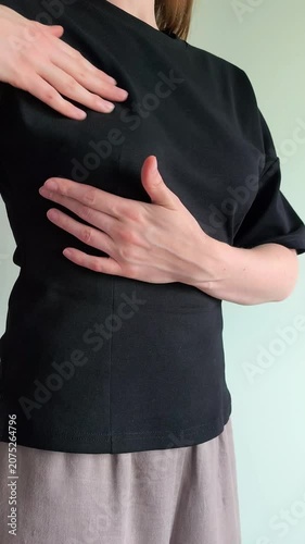 Woman checks her breast for lumps using her hand during a self examination. She feels her chest carefully searching for any unusual changes. Concept of breast self exam, cancer screening and