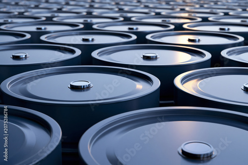 Industrial background with a repetitive pattern of metallic blue oil barrels neatly arranged in rows with soft golden reflection on tops creating a depth of field effect
