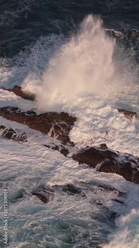 White water surges and recedes around dark, weathered sea stacks in the ocean.