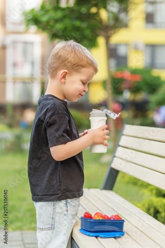 Child having school snack with reusable water bottle outdoors