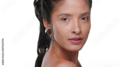 Big close-up shot of argentine woman with honey skin tone strokes her cheek showcasing revitalized skin against white background | Face care commercial