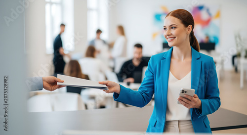 Document handoff in busy office reception shows employee delivering paperwork for manager approval, useful for administrative process, HR form transfer and internal record handling