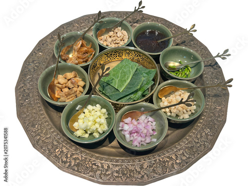 Miang Kham is a traditional Thai snack consisting of various ingredients wrapped in a cha-plu leaf wild betel leaf. A meticulously arranged platter showcases an array of finely chopped ingredients.