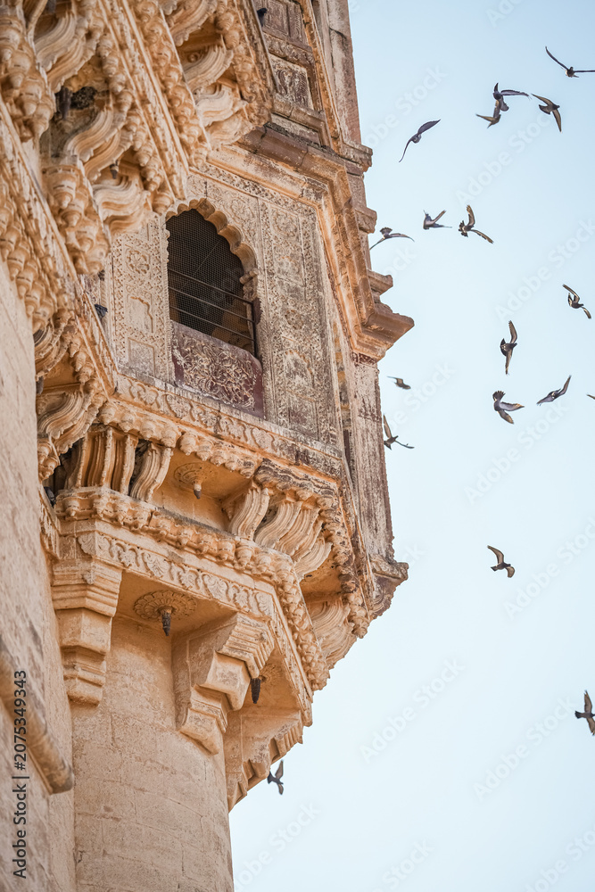 Obraz premium Historic sandstone tower with birds against blue sky 