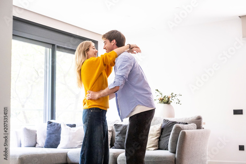 Foto Young couple hugging in a bright living room, smiling and celebrating together w