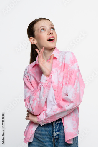 Portrait of teenage girl looking upward with curious and thoughtful expression. Studio shot on white background with copy space, imagination and inspiration concept.