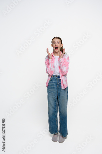 Shocked teenage girl with wide eyes and open mouth expressing surprise, amazement and disbelief. Studio portrait on light background.