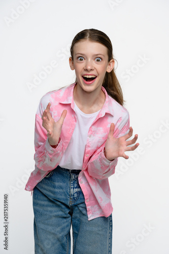 Shocked teenage girl with wide eyes and open mouth expressing surprise, amazement and disbelief. Studio portrait on light background.