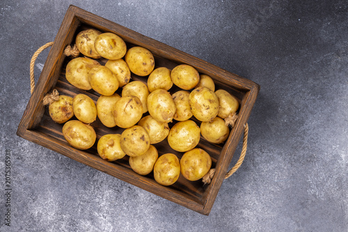 Raw organic young potatoes in wooden basket on gray background
