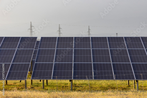Solar panels generating electricity in Almaraz farm against transmission lines