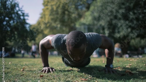 Man doing push-ups outdoors in a park, focusing on fitness and strength