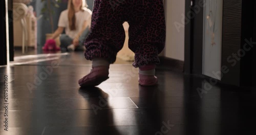 Baby girl making first independent steps on wooden floor. Home lifestyle scene about growing up and mobility