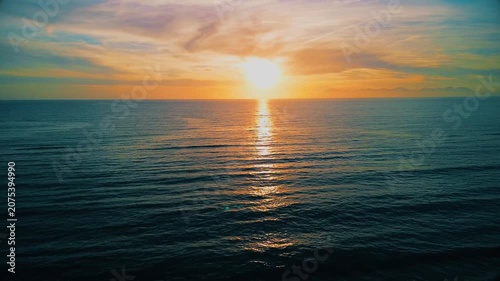 A breathtaking panoramic view of a dramatic golden sunset over the Mediterranean Sea in Agropoli, Cilento coast. The sky is filled with vibrant hues of orange, pink, yellow, and blue clouds, while the