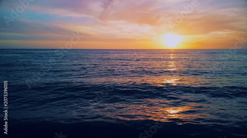 A breathtaking panoramic view of a dramatic golden sunset over the Mediterranean Sea in Agropoli, Cilento coast. The sky is filled with vibrant hues of orange, pink, yellow, and blue clouds, while the