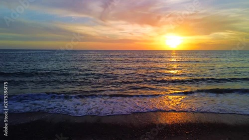 A breathtaking panoramic view of a dramatic golden sunset over the Mediterranean Sea in Agropoli, Cilento coast. The sky is filled with vibrant hues of orange, pink, yellow, and blue clouds, while the