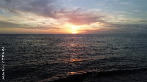 A breathtaking panoramic view of a dramatic golden sunset over the Mediterranean Sea in Agropoli, Cilento coast. The sky is filled with vibrant hues of orange, pink, yellow, and blue clouds, while the