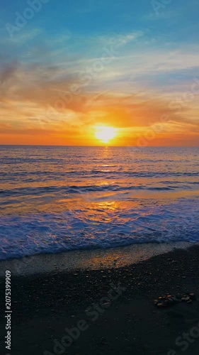 A breathtaking panoramic view of a dramatic golden sunset over the Mediterranean Sea in Agropoli, Cilento coast. The sky is filled with vibrant hues of orange, pink, yellow, and blue clouds, while the