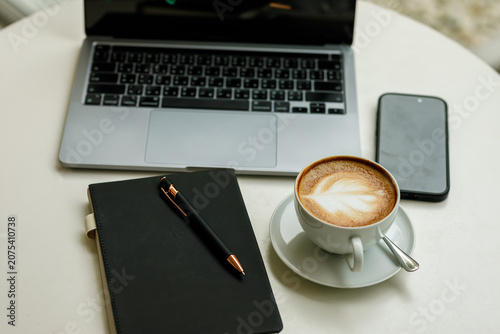 Foto Modern lifestyle concept: a laptop and coffee cup placed next to a notebook on a rustic wooden cafe desk