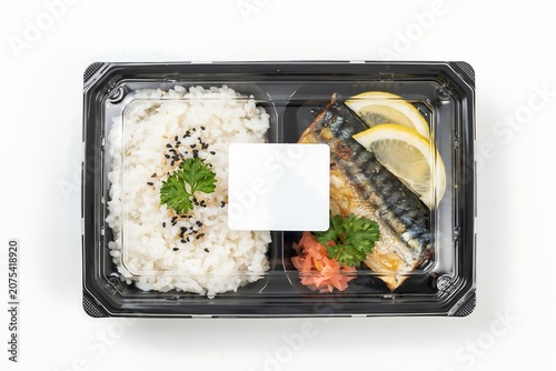 Delicious Japanese style takeout food in plastic container with rice fish and lemon slices