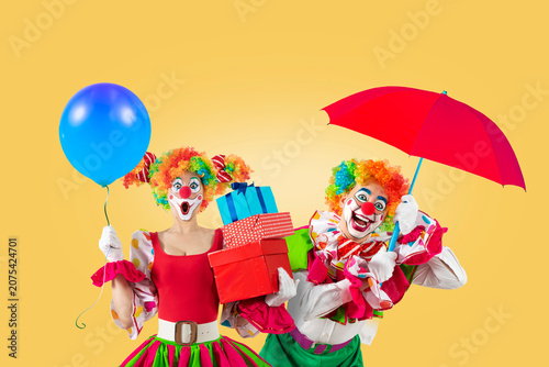 Photos Funny clowns with balloon and umbrella, entertainers in a suit and wig, with clown whiteface makeup