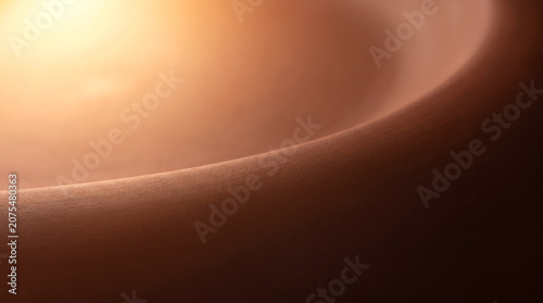 Abstract smooth matte terracotta surface with warm glowing sun flare macro background