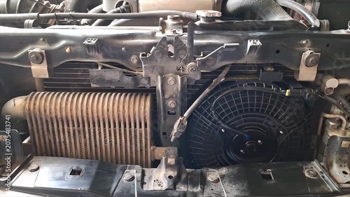 Professional auto mechanic calmly inspecting and servicing a vehicle air conditioning system in a modern, well-equipped auto repair garage.