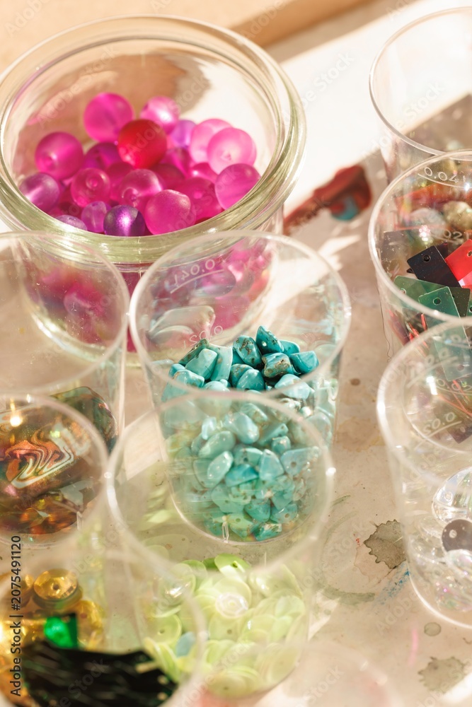 Naklejka premium Artisans engage in a dynamic jewelry making workshop, surrounded by a rainbow of gemstones and creative tools. The atmosphere buzzes with inspiration as they craft unique adornments