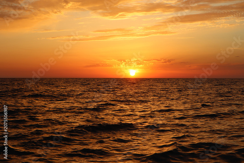 Bright sun on the horizon at sunset over the sea