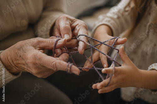 Grandmother and granddaughter playing cat's cradle with string in a close-up of intergenerational connection