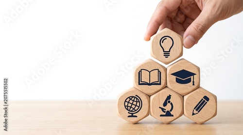 A hand places a lightbulb icon block on a pyramid of educational symbols, representing knowledge, learning, and academic growth.