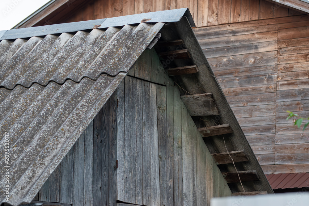 Naklejka premium Old wooden house roof with grey corrugated asbestos slate