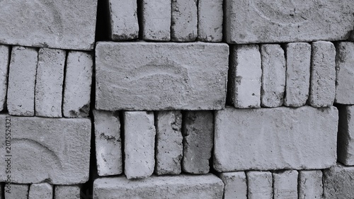 Obraz na plátně Black and white stacked concrete block wall with rough bricks, uneven gaps, dusty marks, and raw construction texture