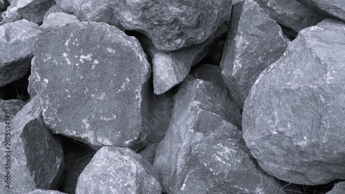 Tableau sur toile Black and white rough stone pile with angular rocks, chalky speckles, shadow gaps, and rugged natural construction texture