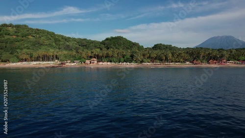 Aerial View of Virgin Beach with Palm Forest, Traditional Boats, Ocean Waves and Mount Agung in Bali