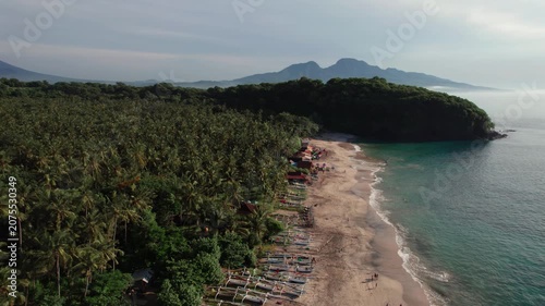 Aerial View of Virgin Beach with Palm Forest, Traditional Boats, Ocean Waves and Mount Agung in Bali