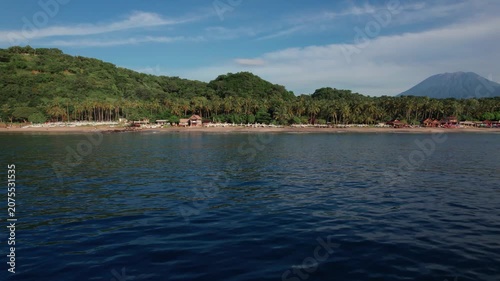 Aerial View of Virgin Beach with Palm Forest, Traditional Boats, Ocean Waves and Mount Agung in Bali