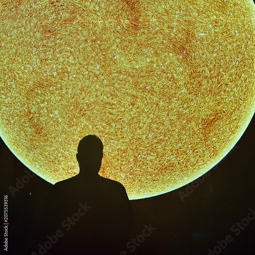 Man shadow over a wall projection of the sun.