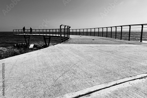 Viewing pier in Paphos, Cyprus with two people at its edge watching the Mediterranean Sea.
