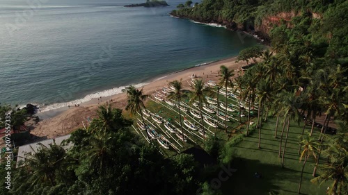 Aerial View of Virgin Beach Bay with Palm Trees, Traditional Boats, Green Cliffs and Blue Ocean in Bali