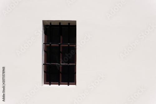 A classic window with decorative bars in the white wall. Krakow. Poland
