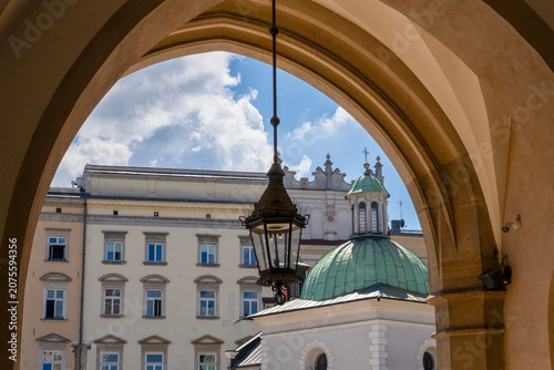 A view from inside the Cloth Hall in Kraków looking out onto the Main Market Square, showing the historic Church of St. Adalbert (Kościół św. Wojciecha) with its distinctive green dome. Krakow, Poland