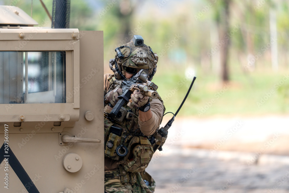 Fototapeta premium One army man point gun to enemy direction and lean on front left door of High Mobility Multipurpose Wheeled Vehicle to practice of fight with enemy.