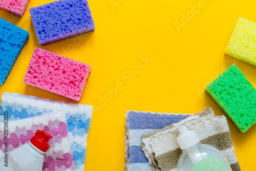 Fotografía Colorful sponges, soft microfiber cloths, and cleaning liquid bottles neatly arranged on a bright yellow background with copy space