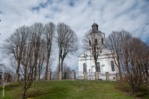White historic church with bell tower and cloudy sky