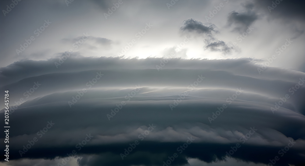 Naklejka premium Dramatic Sky with Dark Clouds and Sunlight Breaking Through Over Landscape