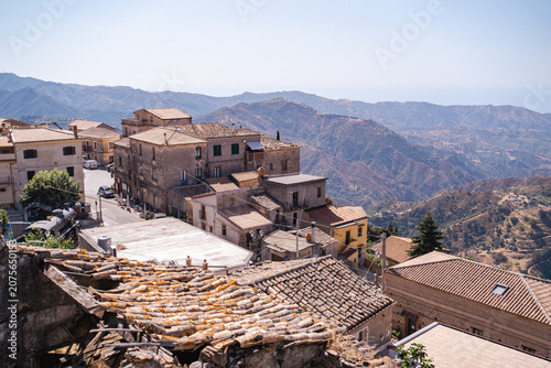 Historic stone houses and tile roofs of Bova town with an old steam locomotive in the background