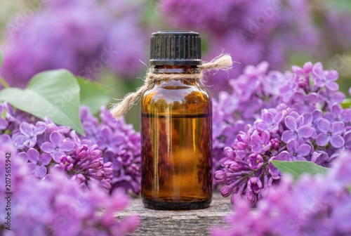 Elegant amber essential oil bottle surrounded by vibrant lilac flowers for aromatherapy