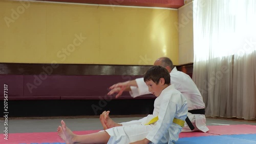 The trainer and the little athlete perform bends to straight legs