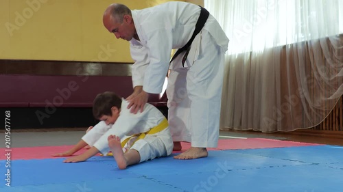 Trainer helps little athlete perform stretching exercise