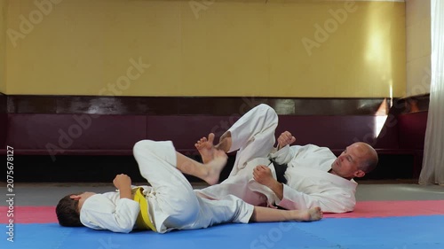 A trainer and a young athlete perform a side kick while lying down